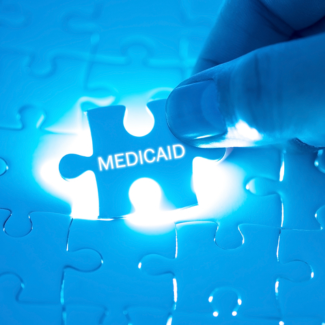 backlit puzzle piece with the word Medicaid printed on it